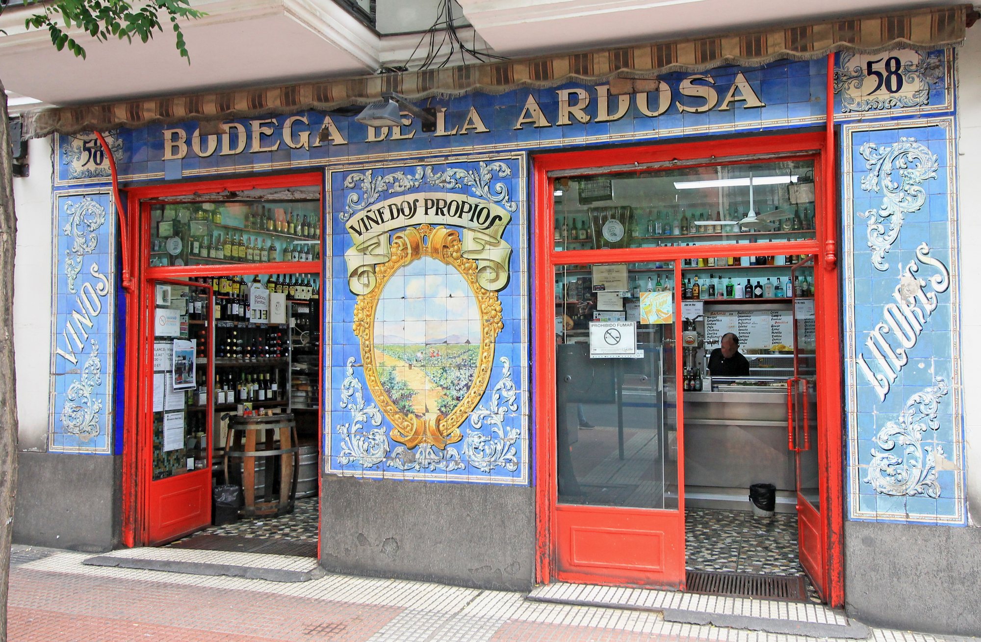 Tiled facade of Bodega de la Ardosa in Madrid, with red doors and blue azulejos